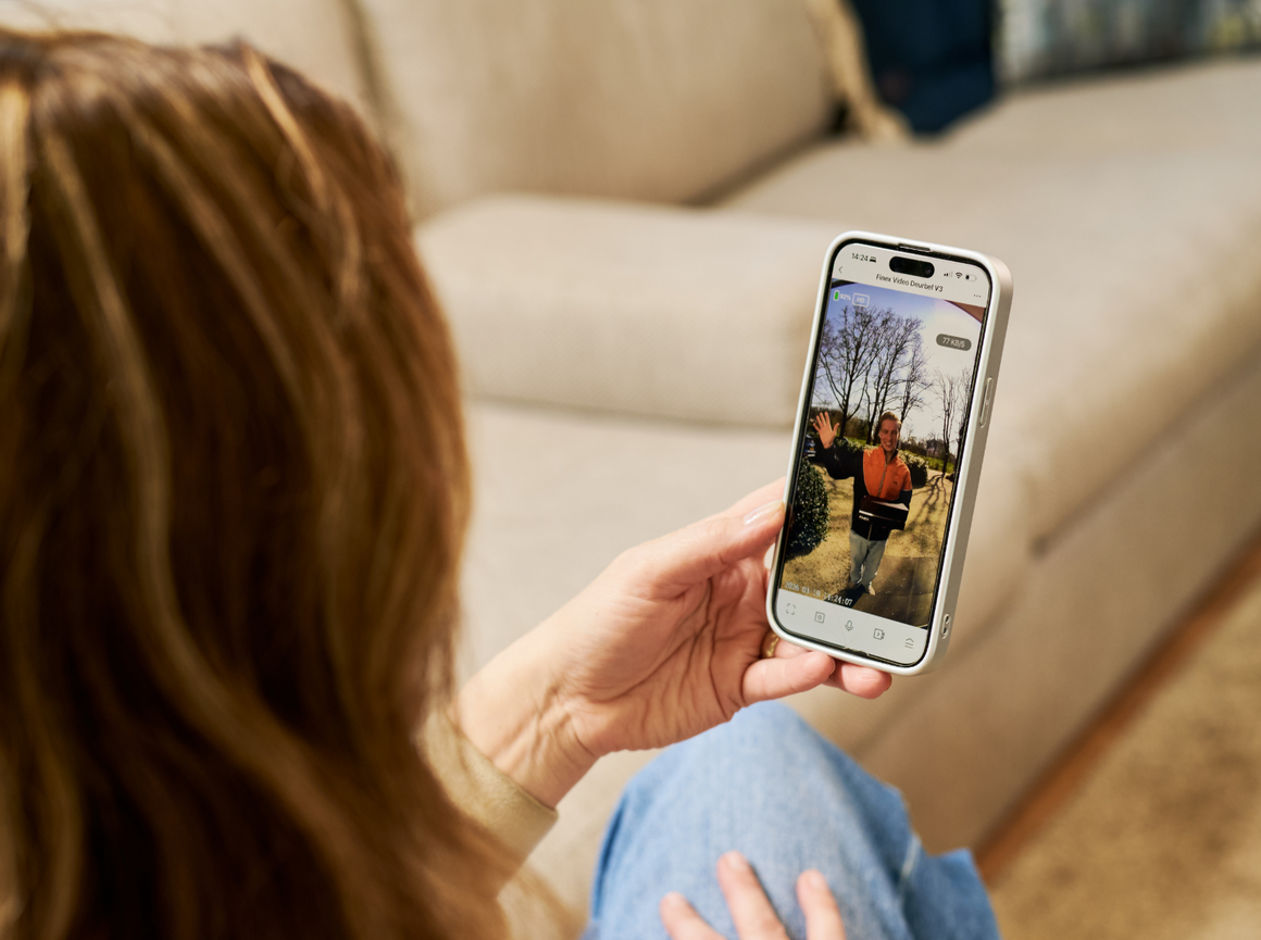 Hand met een telefoon die live camerabeelden van binnen en rond het huis toont