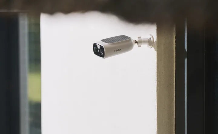 White FINEX outdoor security camera mounted beside a doorway